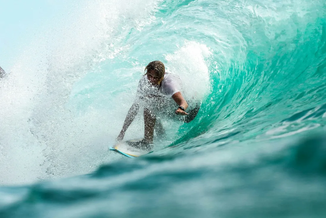 Imagem ilustrativa de um surfista deslizando dentro de uma onda verde